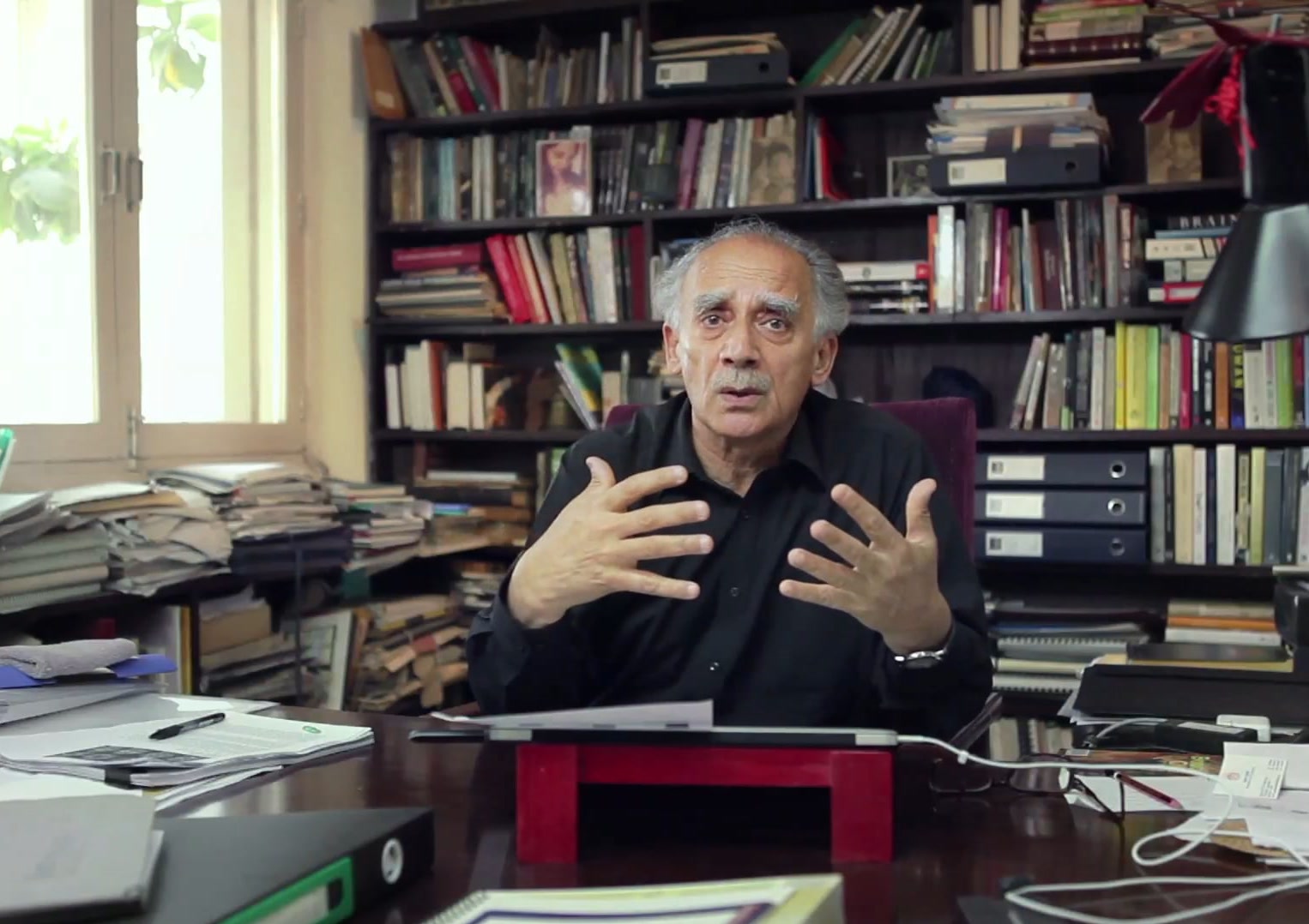 Man speaking in a book lined study, 40 Today